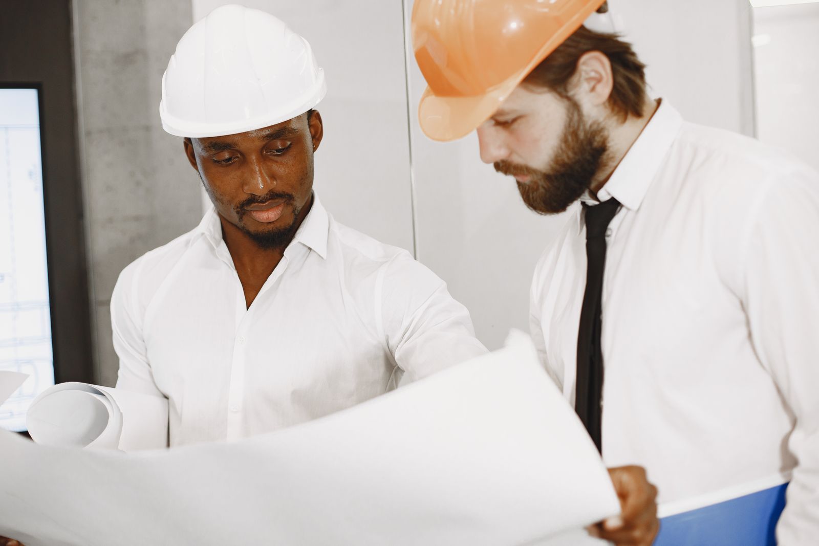 Deux professionnels en casque examinent des plans techniques. Photographie d’illustration.